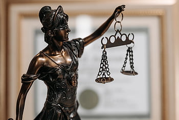 Close-up of a bronze Lady Justice statue holding scales in an office environment. HD wallpaper