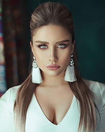 Portrait of a beautiful woman with striking eyes and elegant earrings, captured indoors. HD phone wallpaper