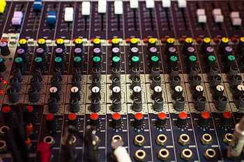 Detailed view of a professional audio mixing console with multicolored knobs in a studio setting. HD wallpaper
