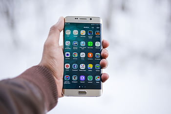 Close-up of a hand holding a Samsung smart displaying various app icons, emphasizing technology and connectivity. HD wallpaper