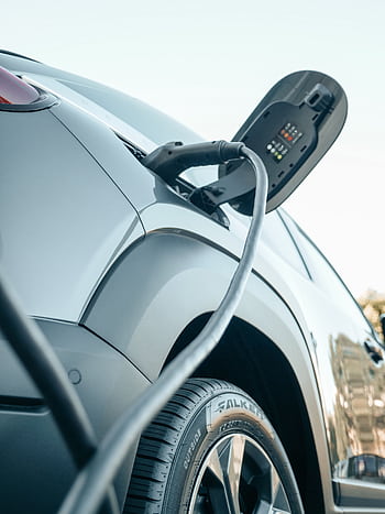 Detailed view of an electric car plugged into a charging station outdoors. HD phone wallpaper