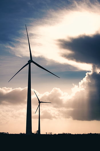 Silhouettes of wind turbines against a cloudy, dramatic sky demonstrating renewable energy. HD phone wallpaper