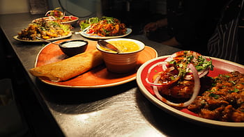 A tantalizing array of Indian dishes including dosa, curry, and chutney served on vibrant plates. HD wallpaper