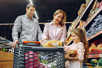 A joyful family of three shopping together in a supermarket, creating a memorable experience. HD wallpaper