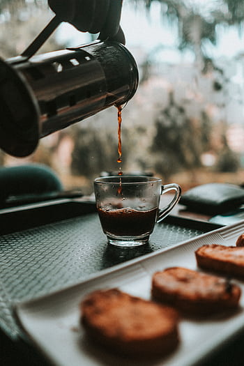 Aromatic coffee being poured into a glass cup beside a plate of biscotti on a tray. HD phone wallpaper