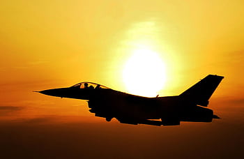 Silhouette of a fighter jet flying during sunrise, highlighting aviation and defense themes. HD wallpaper