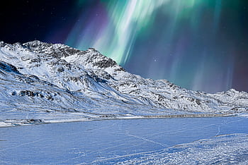 A stunning winter scene with snowcapped mountains and the aurora borealis in the night sky. HD wallpaper
