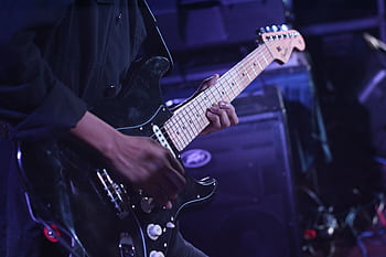 Musician playing an electric guitar on stage during a live performance. HD wallpaper
