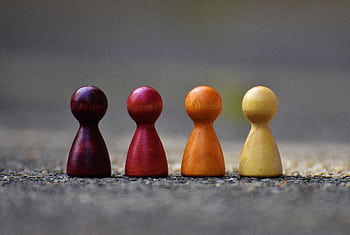 Close-up of four colorful wooden pawn pieces arranged in a row. HD wallpaper