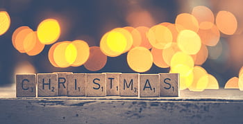 Christmas spelled with Scrabble tiles against a warm bokeh background, perfect for holiday themes. HD wallpaper