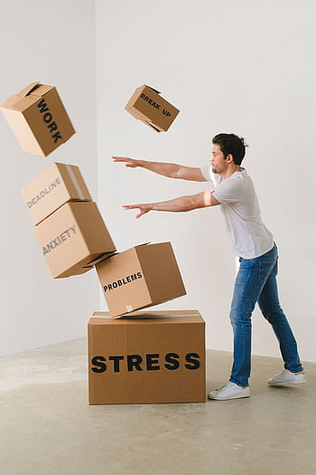 Man facing stress and anxiety, pushing labeled boxes indoors. HD phone wallpaper
