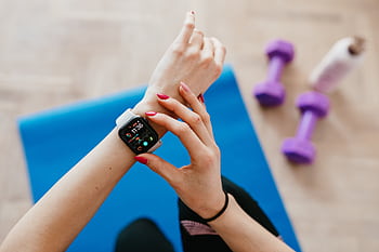 A woman checks fitness data on her smartwatch during a workout at home. HD wallpaper