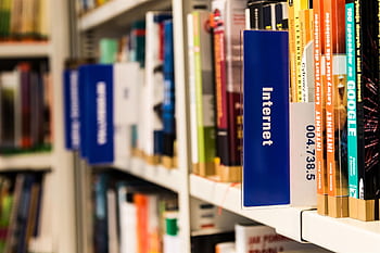 Close-up of a library shelf with books on internet and technology. Ideal for education-themed projects. HD wallpaper
