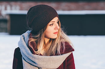 Fashionable woman in beanie and scarf outdoors during winter, showcasing a casual and cozy look. HD wallpaper