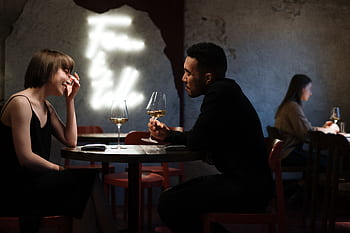 Couple enjoying a romantic evening with white wine in a stylish bar setting. HD wallpaper