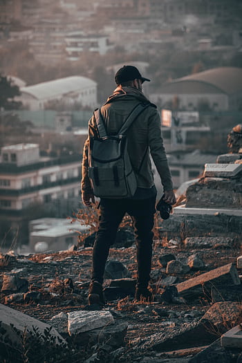 A man explores an urban setting with a camera, capturing the cityscape in the background. HD phone wallpaper