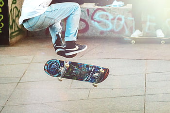 A skateboarder performs an ollie on a sunny day in an urban skate park with graffiti. HD wallpaper