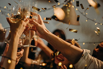 A lively indoor party scene with people toasting champagne glasses amid confetti and warm lights. HD wallpaper