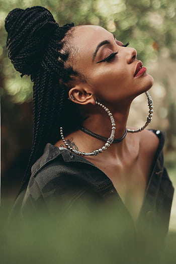 Captivating portrait of a woman with braided hair and stylish jewelry posing outdoors. HD phone wallpaper