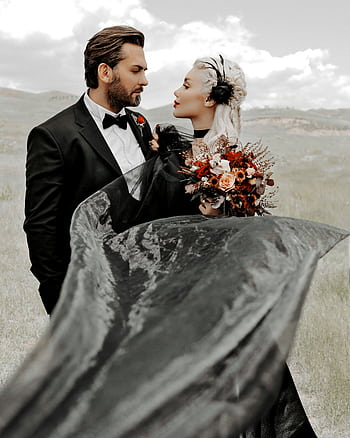 Outdoor wedding of a couple in elegant attire with a black gown and bouquet. HD phone wallpaper