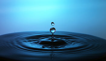 Macro shot of a perfect water droplet splash creating ripples on a blue background. HD wallpaper