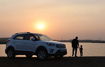 A touching silhouette of a father and son beside a car at sunset by a lake in Bhopal, India. HD wallpaper