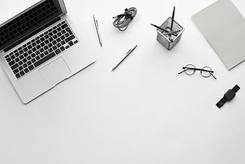 Top view of a minimalist workspace featuring a laptop, glasses, and office supplies on a white desk. HD wallpaper