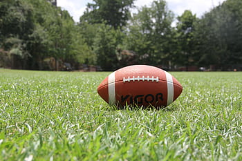 A close-up of an American football on a grassy field, highlighting outdoor sports in summer. HD wallpaper