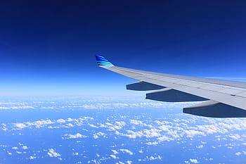 Scenic view of an airplane wing flying high above the clouds on a clear day. HD wallpaper