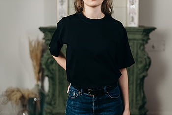 Faceless model in black t-shirt and jeans showcasing minimalist fashion style indoors. HD wallpaper