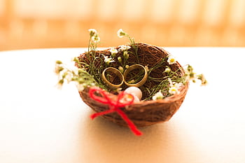Golden wedding rings nestled in a floral basket symbolizing love and commitment. HD wallpaper