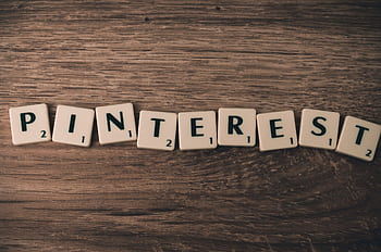 Scrabble tiles spelling Pinterest on a wooden background, symbolizing social media and creativity. HD wallpaper