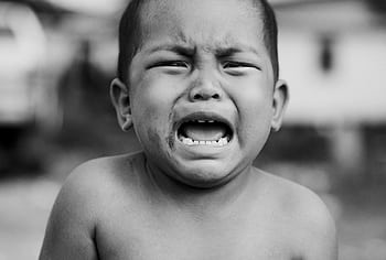 Heartfelt portrait of a young child crying, showcasing raw emotion in black and white. HD wallpaper