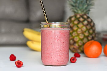 A refreshing pink smoothie made with bananas, raspberries, and tropical fruits in a glass jar. HD wallpaper