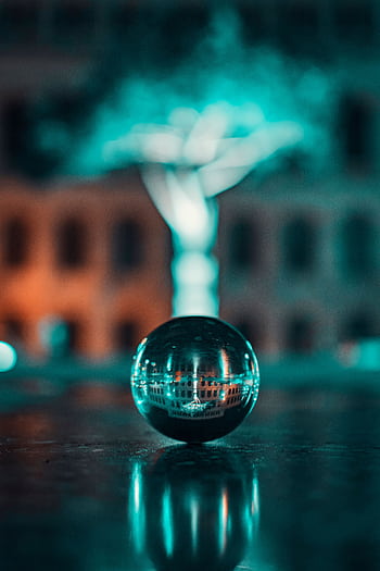 Artistic night shot of a crystal ball reflecting an urban backdrop with vivid lighting. HD phone wallpaper