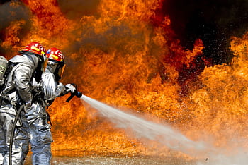Brave firefighters in action extinguishing a large fire with determination and teamwork. HD wallpaper