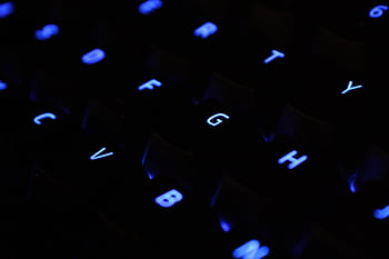 A detailed shot of blue backlit keyboard keys in a dark setting. HD wallpaper