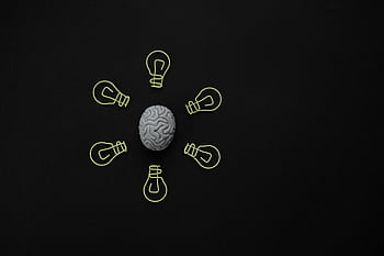 Conceptual of a brain surrounded by light bulb clips on black background. HD wallpaper