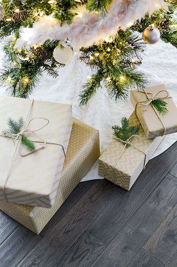 Beautifully wrapped Christmas gifts under a festive tree with glowing lights. HD phone wallpaper