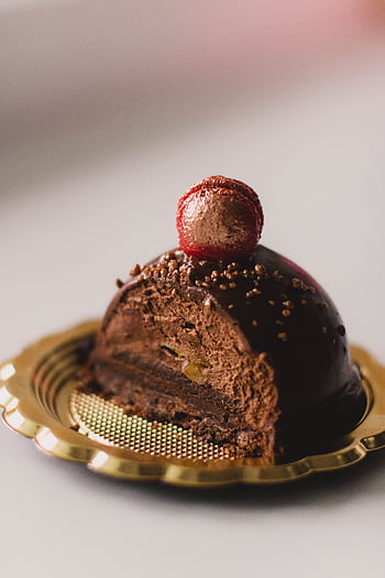 Indulge in a rich chocolate cake slice topped with a decorative berry for a gourmet dessert experience. HD phone wallpaper