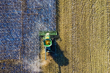 Aerial drone shot of a combine harvester working in a cornfield during harvest season in rural Minnesota. HD wallpaper
