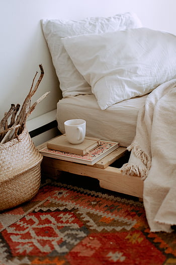A cozy boho-style bedroom corner with books, a mug, and elegant decor. HD phone wallpaper