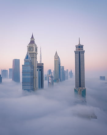 A breathtaking aerial view of Dubai's iconic skyline emerging through the clouds at sunrise. HD phone wallpaper