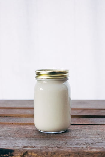A rustic glass jar filled with creamy yogurt, placed on a wooden table. Ideal for healthy food themes. HD phone wallpaper