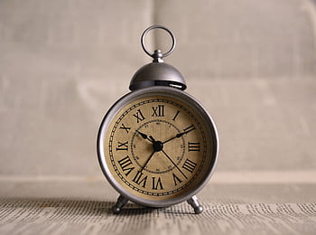 Close-up of an antique alarm clock displaying time with classic Roman numerals. HD wallpaper