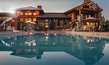 Stunning wooden villa with a large pool and cozy lights, perfect for a luxurious escape. HD wallpaper