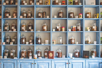 Organized display of herbal tea jars on vibrant blue shelves in a shop. HD wallpaper