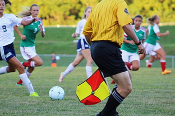 Women's soccer match featuring players and referee on field in motion. HD wallpaper
