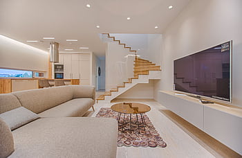 Spacious modern living room featuring stairs, a TV, and sleek furniture design. HD wallpaper