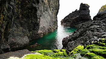 Stunning coastal rock formation with vibrant moss and clear water, perfect for nature enthusiasts. HD wallpaper